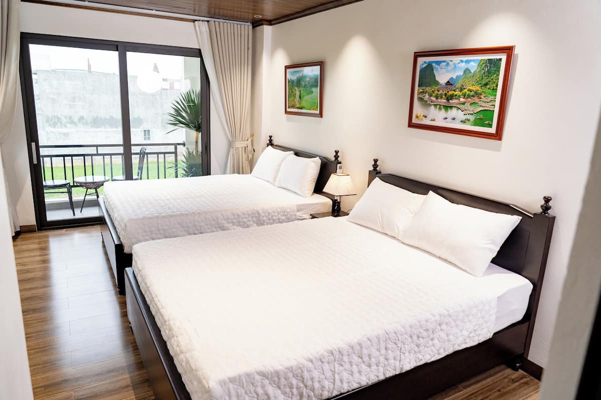 A hotel room with two beds, a balcony, and two framed pictures on the wall.