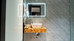 A bathroom with a marble countertop, a white sink, a mirror with LED lighting, and a shower area. - TAM COC HA ANH HOTEL (Nam Hoa Lu)