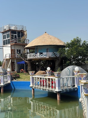 Een huis met rieten dak, een balkon en een waterpartij.