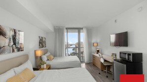 Ett hotellrum med två sängar, ett skrivbord, en TV och utsikt över staden.
