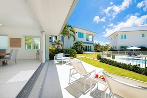 A modern house with a pool, outdoor seating, and a well-maintained lawn.