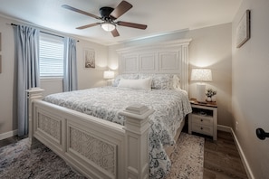 A bedroom with a bed, a nightstand, a lamp, a ceiling fan, and a window with curtains. - The Magnolia Cottage: Escape the big City- Charming Cozy house in La Vernia! (La Vernia)