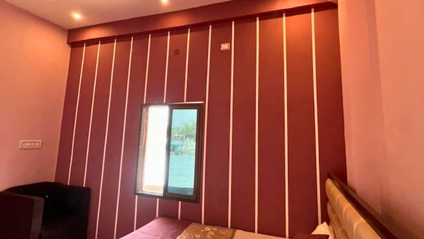Ein Schlafzimmer mit Bett, Deckenventilator, Fenster und an der Wand befestigtem Fernseher.