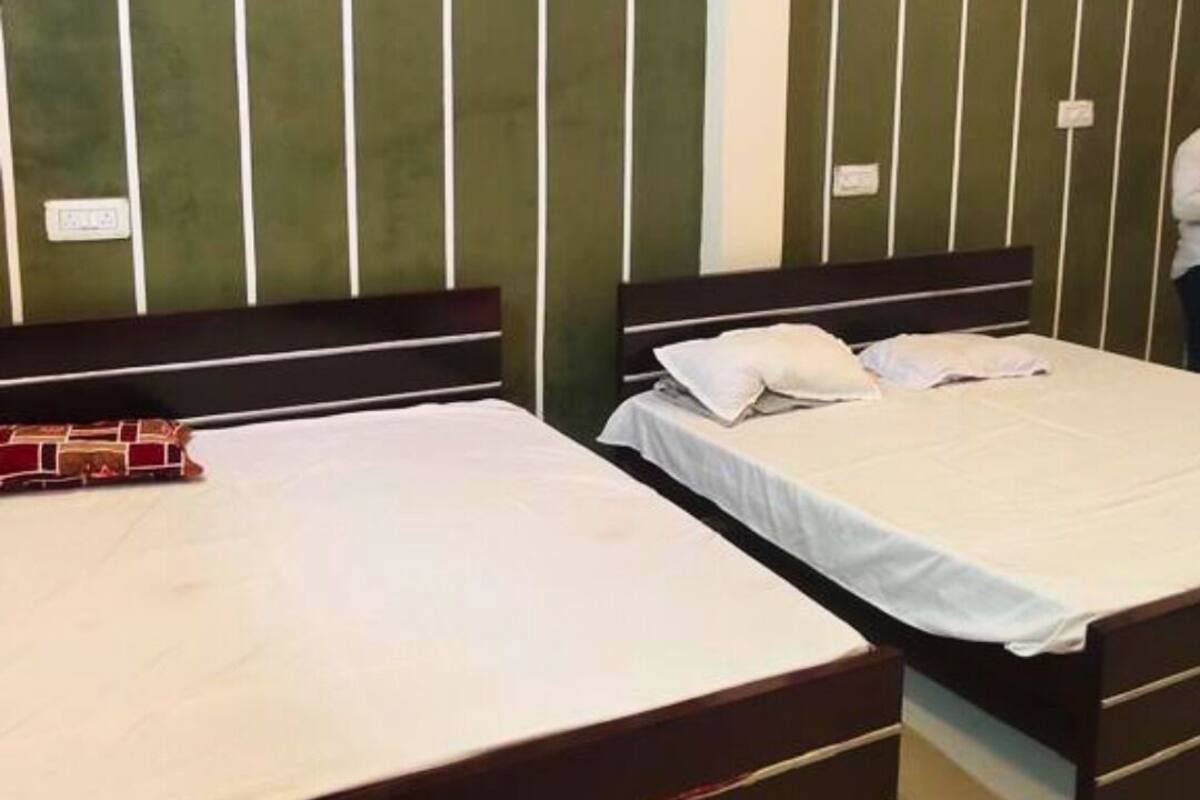 A hotel room with two single beds, a wooden headboard, and a green striped wall.