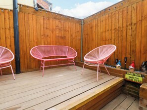 A wooden deck with three pink chairs and a caution sign. - Wick Cottage (Whitby)