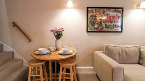 Ein Essbereich mit einem Holztisch, vier Hocker, einer Blumenvase und einem Poster an der Wand.