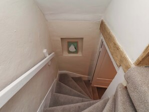 A narrow stairway with carpeted steps, a white handrail, and a small framed picture on the wall. - Wick Cottage (Whitby)