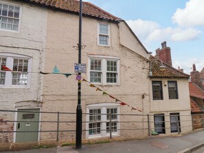 A building with a white facade, multiple windows, and a sign indicating a parking zone. - Wick Cottage (Whitby)