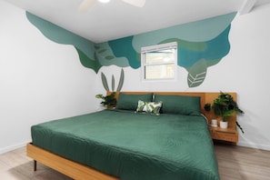 A bedroom with a bed, a window, and two bedside tables with plants.