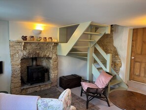 A stone fireplace with a modern staircase, a wicker chair, and a wooden door. - Quaint Townhouse in the Centre of Chipping Norton (Chipping Norton)