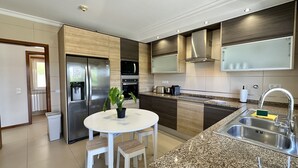 Een moderne keuken met een roestvrijstalen koelkast, dubbele oven, magnetron, granieten aanrechtblad en een gootsteen met kraan.