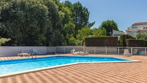 Ein rechteckiger Pool mit einer befliessten Kante, umgeben von einer gepflasterten Terrasse mit Verbundsteinen.
