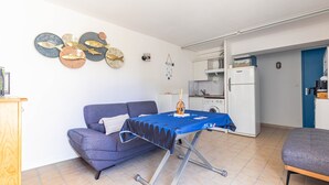 Ein gemütlicher, kompakter Wohnbereich mit Sofa, klappbarem Tisch, Küchenzeile und dekorativen Wandbildern.