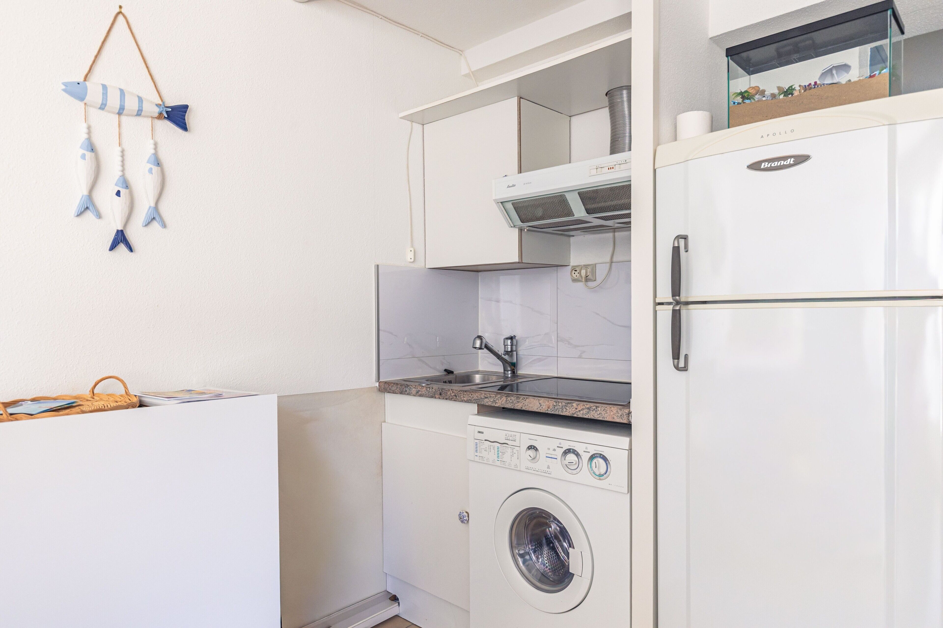 Cocina compacta con horno integrado, microondas y lavadora.