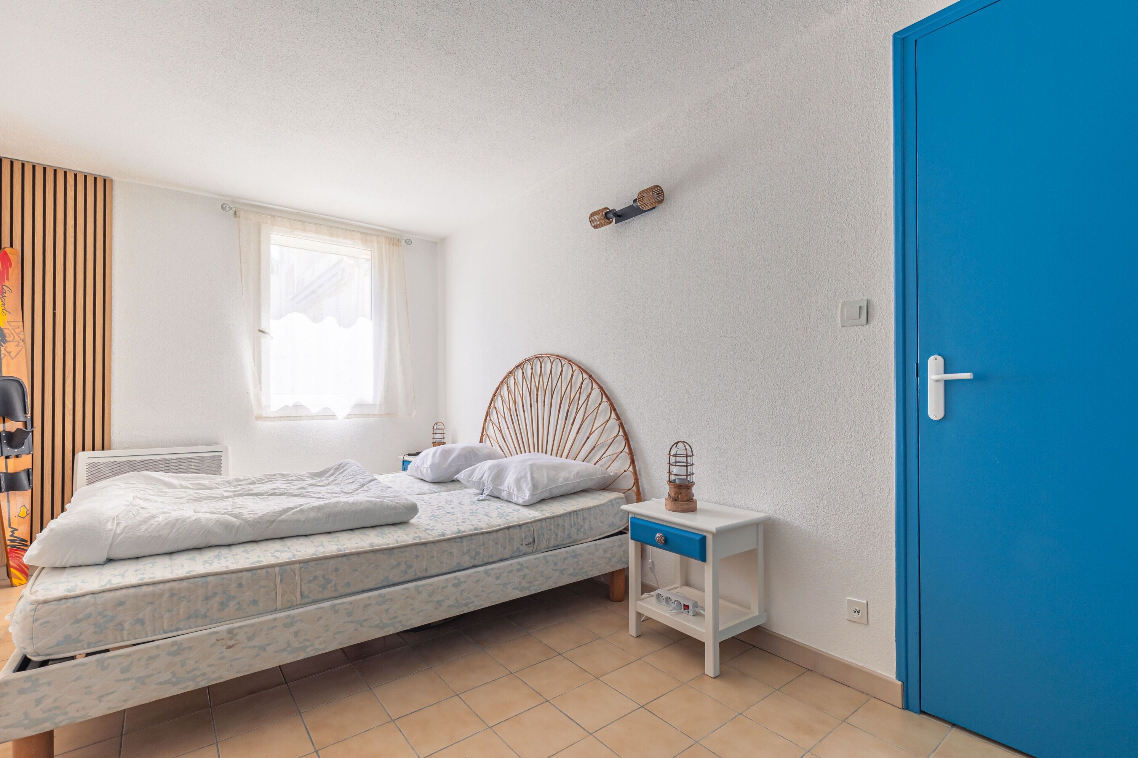 Une chambre à coucher avec un lit, une table de chevet, une lampe et une porte bleue.