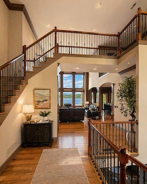 Un interior de varios niveles con una escalera de madera, una sala de estar con vistas y un comedor.