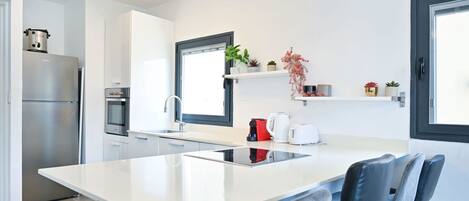 Una cocina moderna con una isla central, electrodomésticos de acero inoxidable y un diseño minimalista.