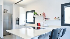 A modern kitchen with a central island, stainless steel appliances, and a window with a view. - Hayarkon Joie in Tel Aviv-yafo (Tel Aviv)