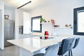 Eine moderne Küche mit Kochinsel, Edelstahlgeräten und einem Fenster mit Aussicht.