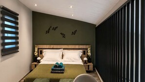 A modern bedroom with a bed, bedside tables, a desk, and a chair. - Epanomi Suites - Modern Living With Garden Retreat (Thermaikos)