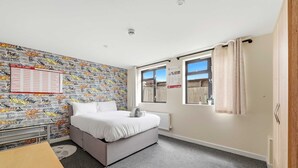 A bedroom with a bed, a window, a radiator, a wall calendar, and a door. - 6-bedroom Family Haven With Garden in Aylesbury (Aylesbury)