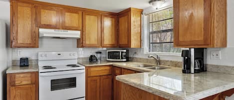 Una cocina con armarios de madera, estufa blanca, microondas y cafetera.