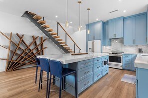 Eine moderne Küche mit blauen Schränken, einer Holztreppe und einer Marmorarbeitsplatte.