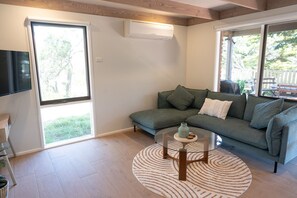 A living room with a sectional sofa, a glass coffee table, and a large window. - Serene Family Retreat - Relax in Modern Comfort (Melbourne)