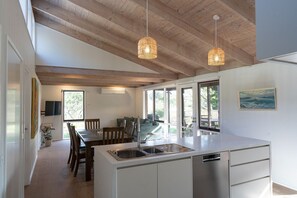 A modern kitchen with a central island, pendant lights, and a view to the outside. - Serene Family Retreat - Relax in Modern Comfort (Melbourne)
