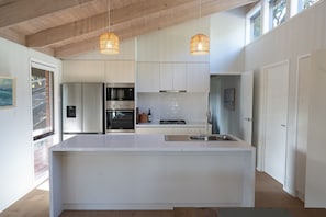 A modern kitchen with a central island, stainless steel appliances, and pendant lighting. - Serene Family Retreat - Relax in Modern Comfort (Melbourne)
