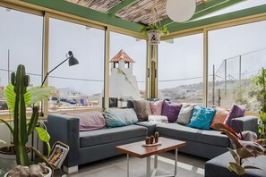 A modern living room with a grey sofa, colorful cushions, a small table, and a cactus plant.
