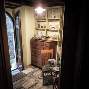 Une cuisine compacte avec un meuble en bois, une chaise, une petite table et un mur en pierre.