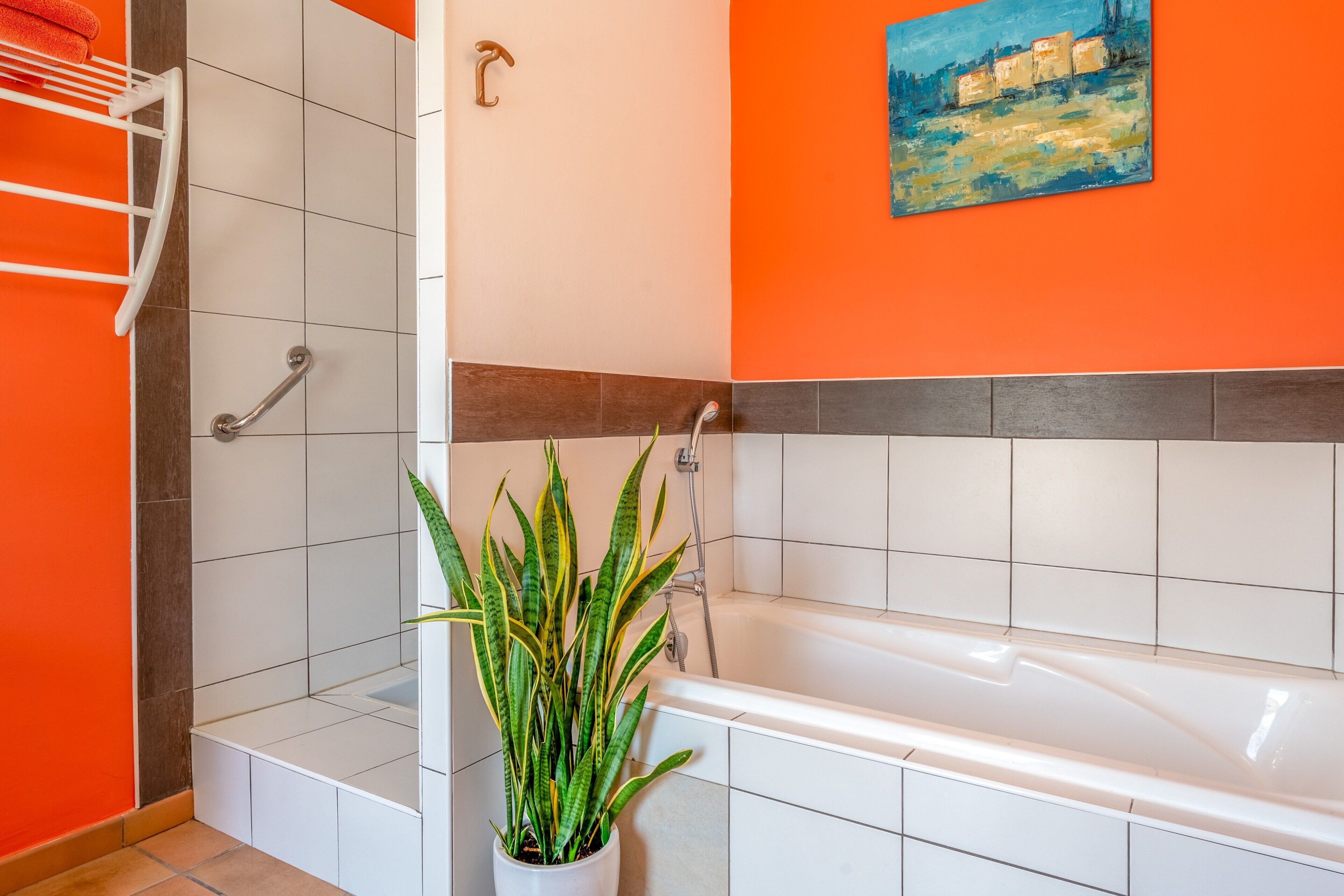 A bathroom with a bathtub, a shower, a towel rack, and a potted plant.
