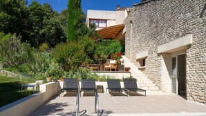A pool area with lounge chairs, a stone building, and a garden with various plants. - Orchidée Guest Room with Shared Pool, Wi-Fi, and Air Conditioning (Lagarde-Paréol)