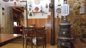 Un intérieur rustique avec un mur en pierre, des meubles en bois et un poêle d’époque.