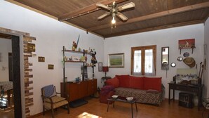 Un salon comprenant un canapé, une table basse en bois, une cheminée et un ventilateur de plafond.