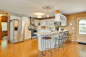 A modern kitchen with stainless steel appliances, wooden flooring, and a central island with bar stools. - Lakefront Home w/ Covered Dock & Game Room (Denver)