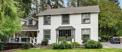 A two-story house with a porch, a covered front entrance, and a well-maintained lawn.
