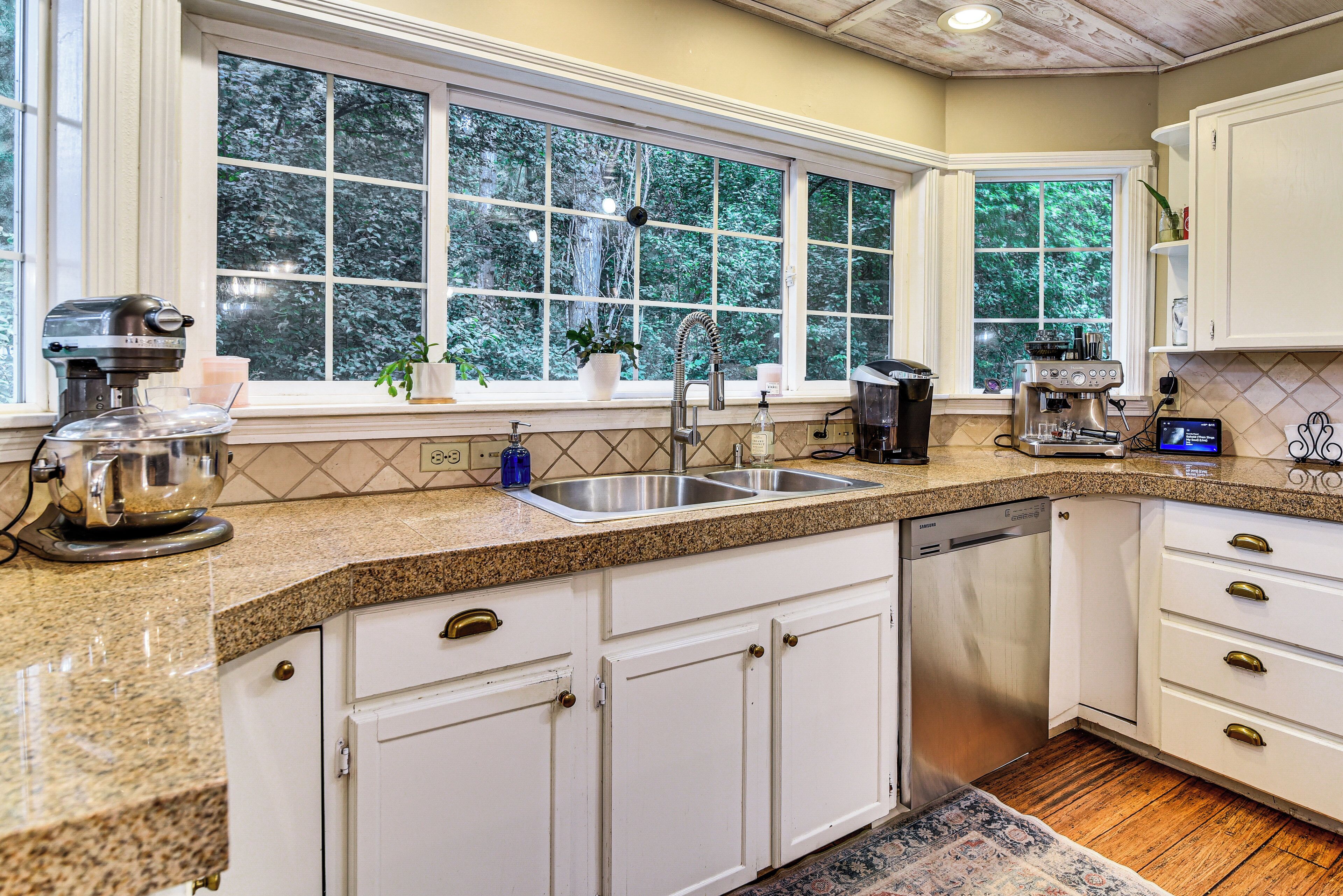 A kitchen with a window, a coffee maker, and a dishwasher.