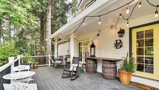 A wooden deck with outdoor seating, a bar area, and a door with a nameplate.