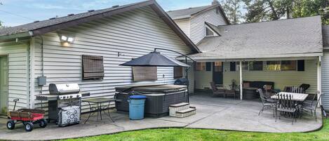 A backyard with a grill, hot tub, and outdoor furniture.