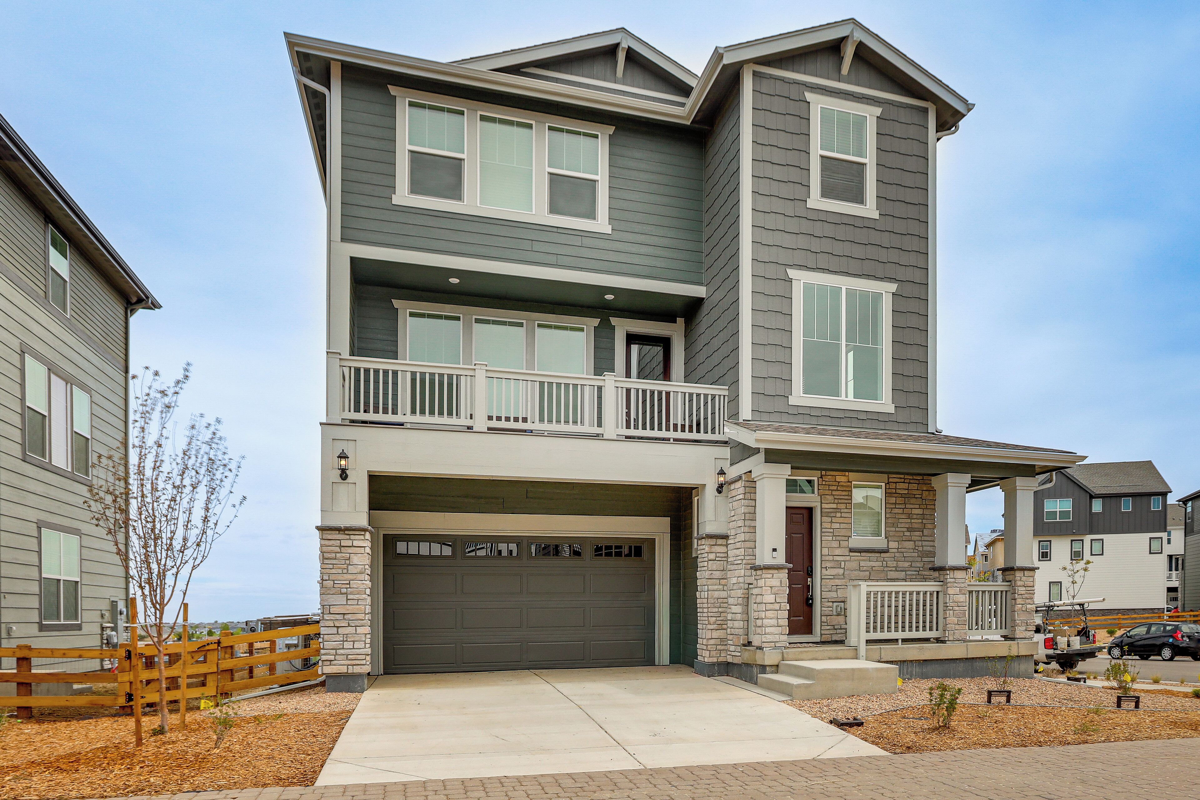 A two-story residential building with a garage, a balcony, and a stone facade.