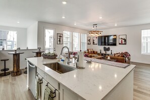 A spacious kitchen with a large island, modern appliances, and a dining area with a sofa and TV. - Pets Welcome! Thornton Extended Stay w/ Balcony (Thornton)