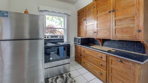 Una cocina con un refrigerador de acero inoxidable, horno, microondas, gabinetes de madera y una ventana.