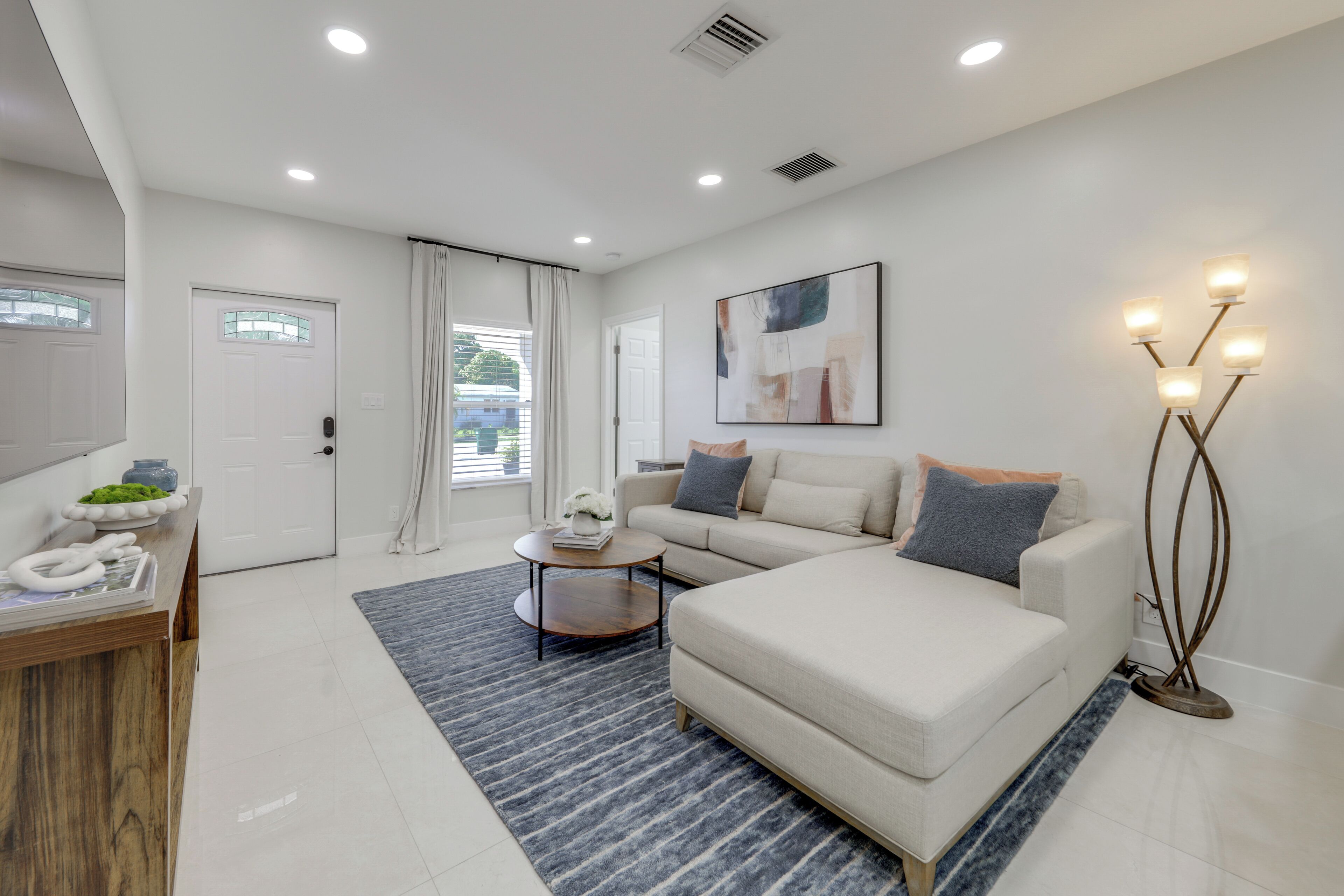 A modern living room with a sofa, a coffee table, a floor lamp, and a painting on the wall.