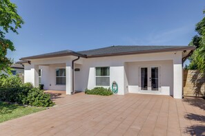 Ein modernes, zweistöckiges Haus mit gepflasterter Auffahrt, überdachter Terrasse und sichtbarem Garagentor.
