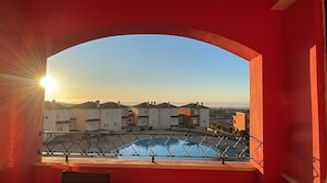 Ein Balkon mit Blick auf einen Swimmingpool und eine Reihe von Gebäuden im Hintergrund.