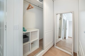 A walk-in closet with open doors, shelves, and a hanging rack.