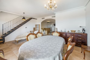 A spacious living room with a large bed, a dining table, and a staircase leading to another level.