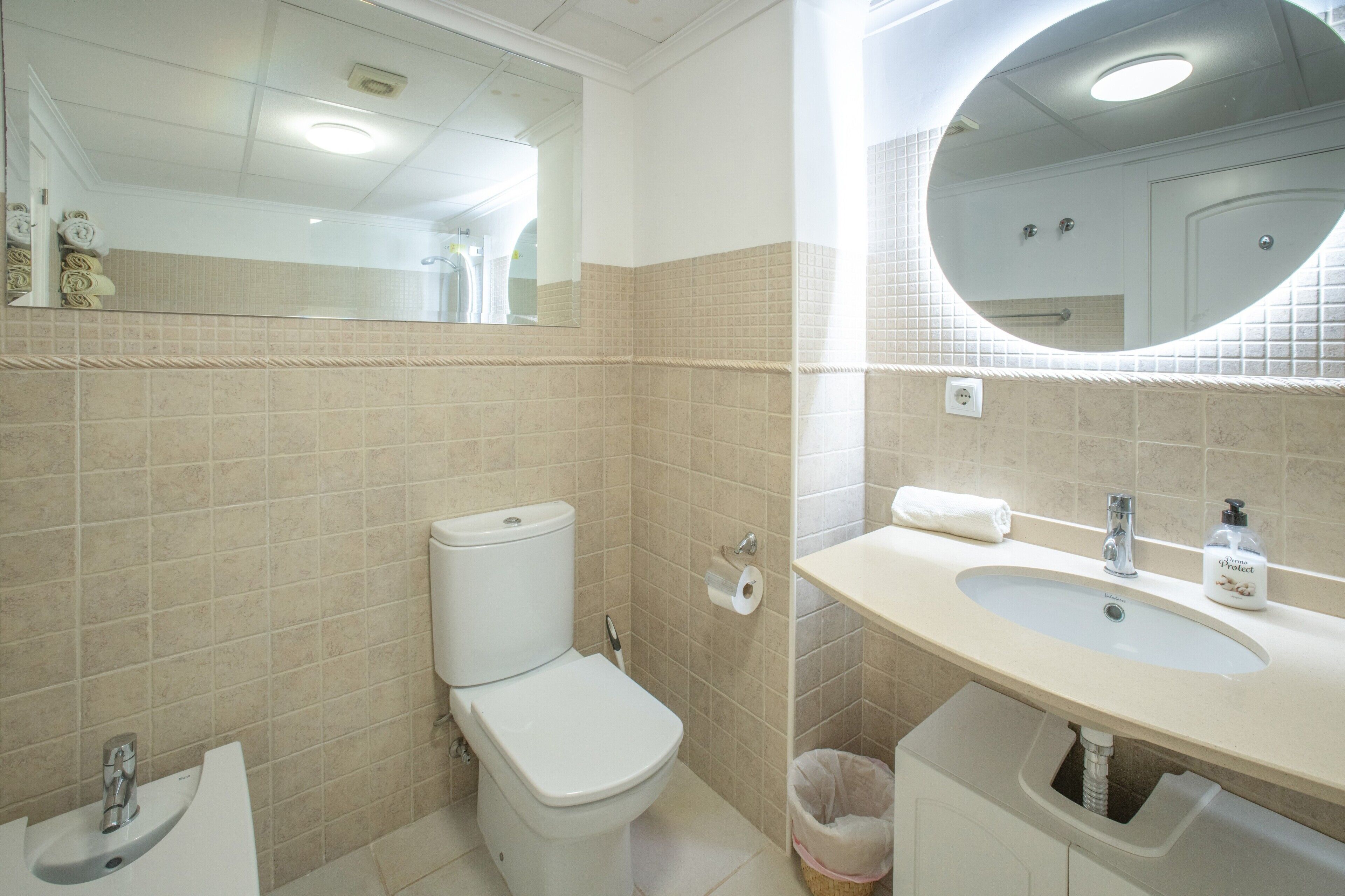 Ein Badezimmer mit Toilette, Waschbecken, Spiegel und Handtuchhalter.